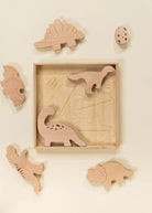 Wooden dinosaur puzzle with pieces displayed on a beige background