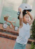 Child wearing a helmet indoors with a bicycle in the background