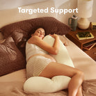 Woman lying on a bed with targeted support pillows, surrounded by a cozy bedroom setting.