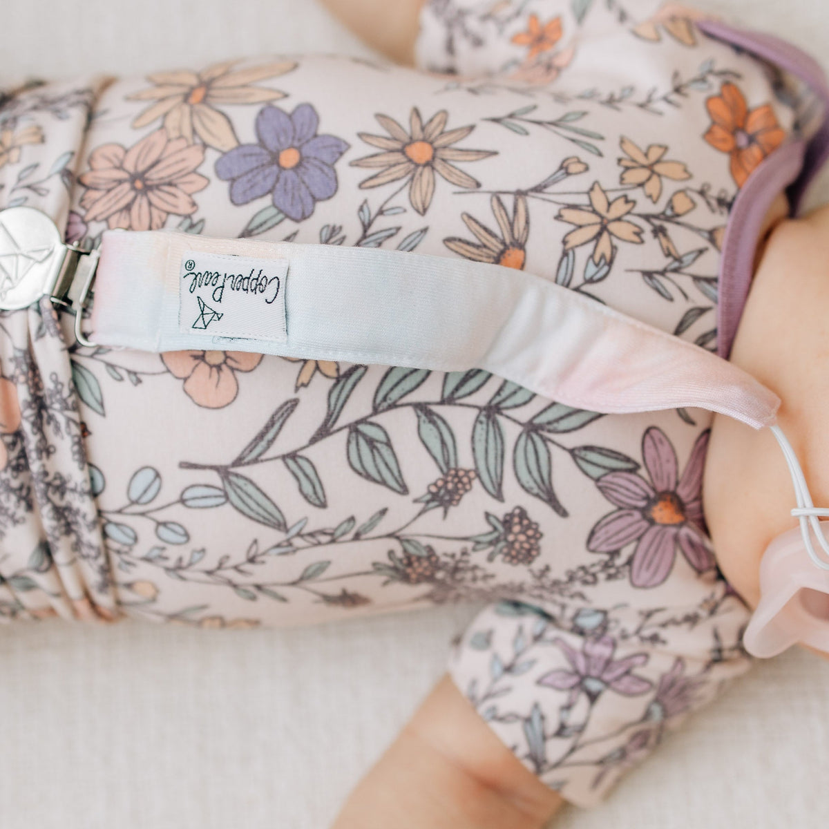 Floral-patterned baby outfit with a visible brand label on a soft background