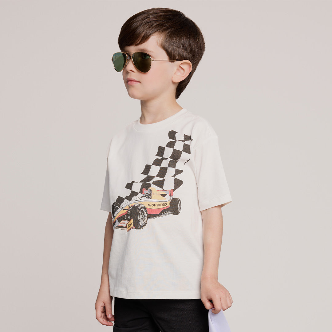 Child wearing a t-shirt with a race car and checkered flag design on a plain background