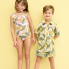 Two children wearing banana-patterned clothing on a yellow background