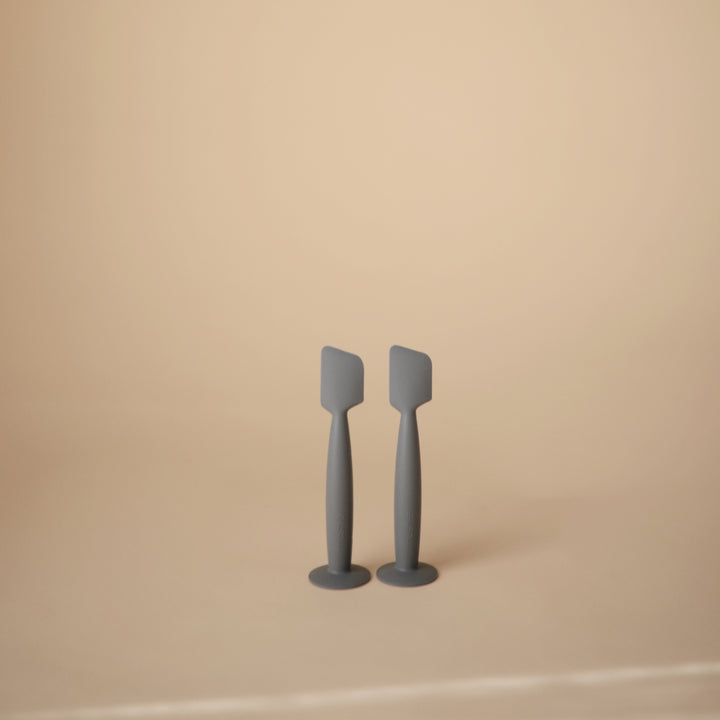 Two gray spatulas on a beige background