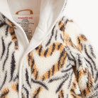 Close-up of a plush fleece zip-up hoodie with a tiger-stripe pattern in cream, tan, and dark gray/black. The inner collar shows the brand name 'magnetic me' and size information.