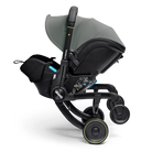 A Diaperas stroller system in black and dark gray, featuring a black infant car seat, a gray canopy, and black wheels with yellow accents, shown on a clean white background.