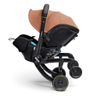 A Diadora stroller and bassinet combo in black and tan/caramel, shown from a side profile on a clean white background.