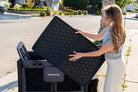 Woman opening a black pet carrier with 'Wondersport' branding on a sidewalk.