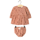 A toddler girl's two-piece clothing set featuring a long-sleeve peplum top and matching bloomers, both in a dusty terracotta color with a brown leaf pattern, hanging on a wooden hanger against a white background.