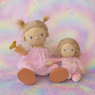 Two dolls with blonde hair and pink outfits on a colorful, rainbow-patterned background.