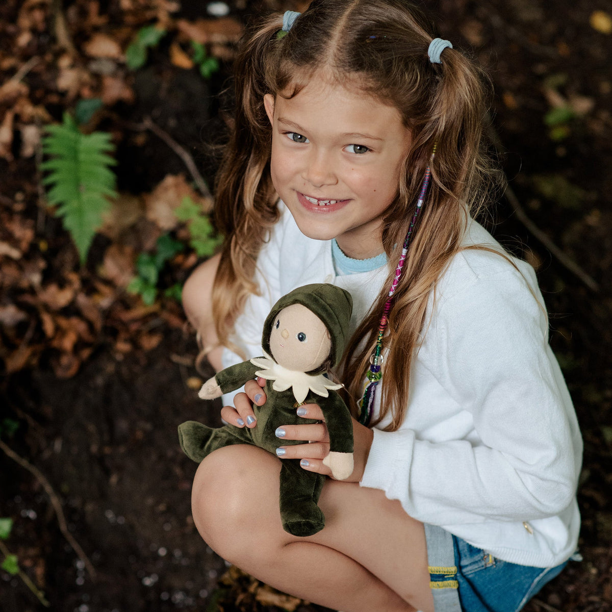 Young girl holding a doll in a forest setting