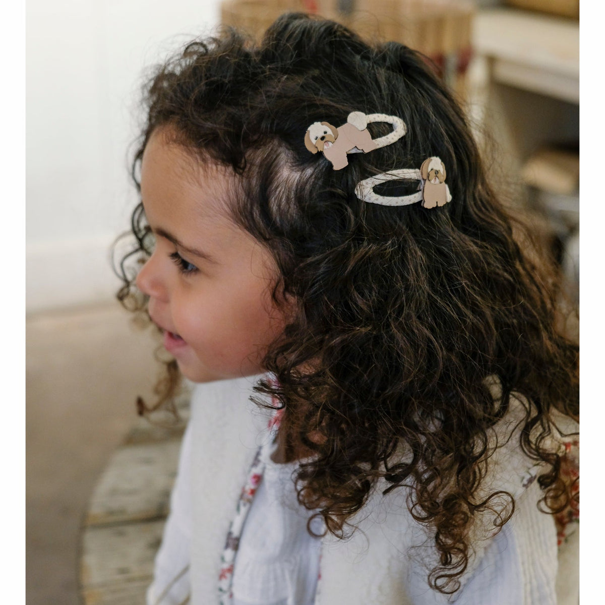Child with curly hair wearing a headband with animal designs.