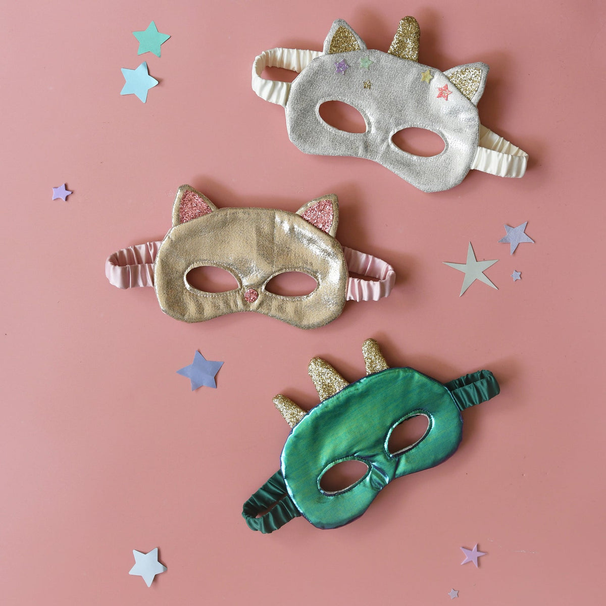 Three colorful masks on a pink background with star decorations
