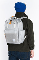 Person wearing a gray backpack with a visible brand logo on a white background