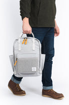 Person holding a gray backpack with a transparent side panel on a white background