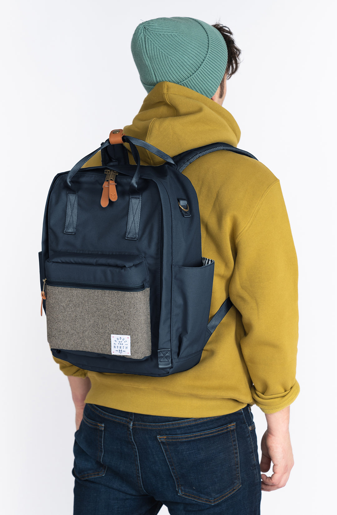 Person wearing a navy blue backpack with gray front pocket on a white background