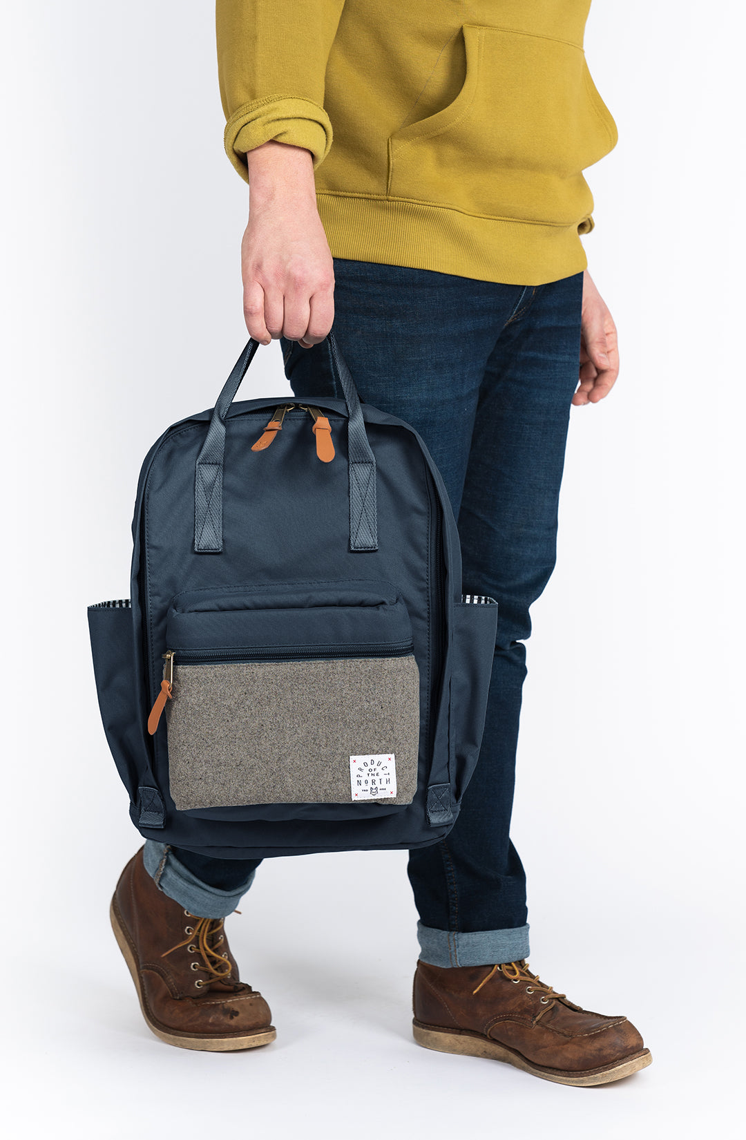 Person holding a navy blue backpack with a gray patch on a white background