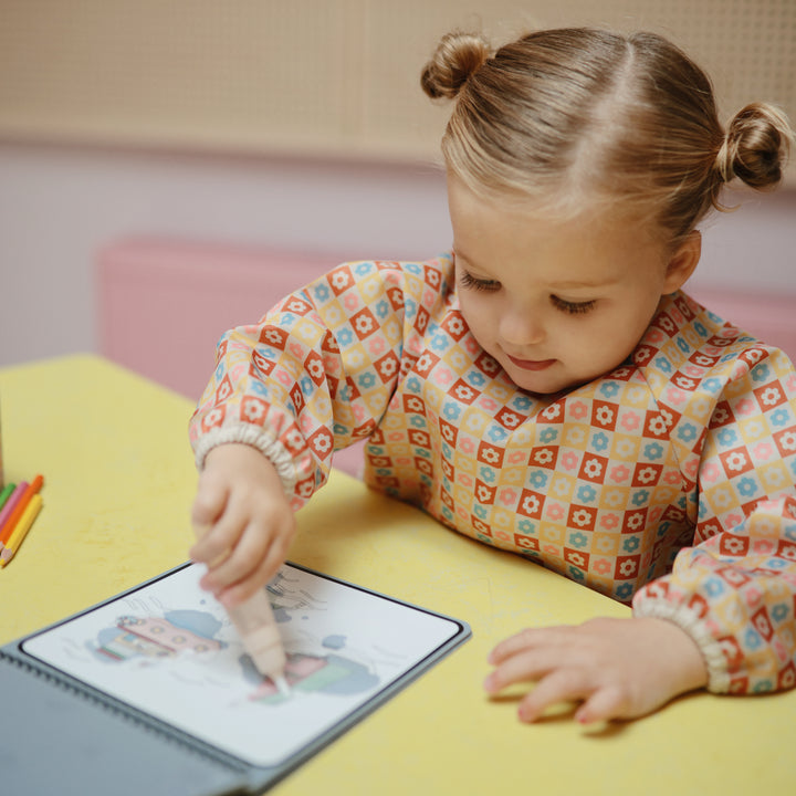 Child interacting with a tablet on a yellow table