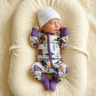 Newborn baby in a colorful outfit and white hat lying on a textured beige surface