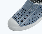 Close-up of a blue shoe with perforated design on a white background