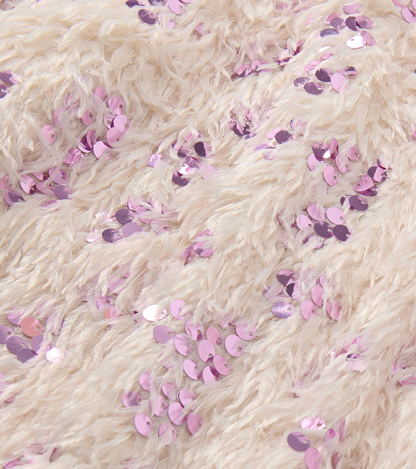 Close-up of fluffy cream faux fur fabric scattered with pink, lavender, and purple sequins.