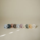 Row of colorful pacifiers on a beige background