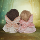 Two children wearing fairy wings in a magical forest setting