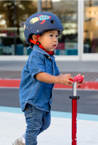 Child wearing a helmet and riding a scooter on a playground.