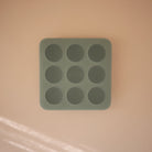Mint green silicone baby food freezer tray and round mold on a white background