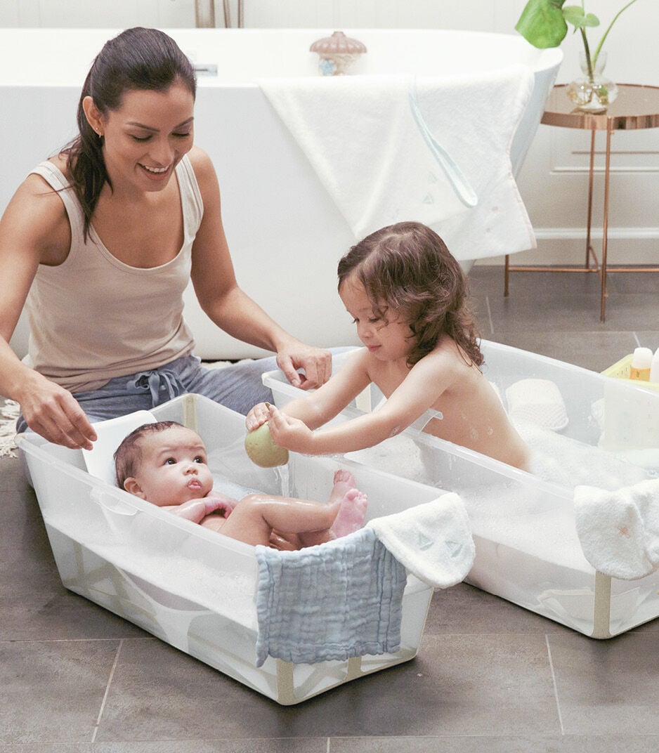 Woman and two children in a portable bathtub with a baby inside.