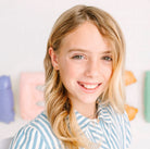 Young girl with blonde hair wearing a striped shirt against a light background