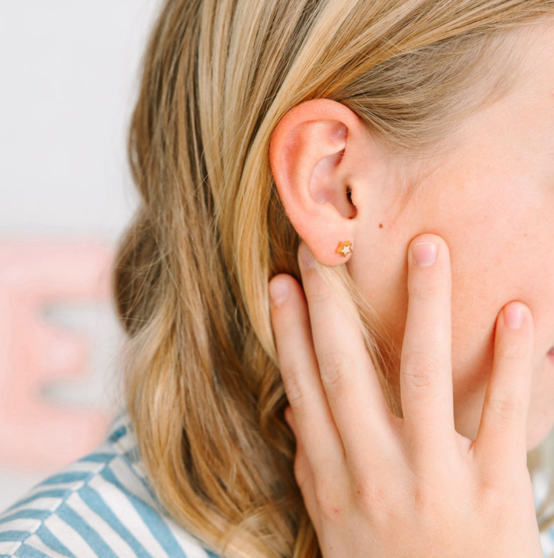 Close-up of a person wearing a gold earring with a blurred background