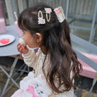 Child with decorative hair clips eating a cookie outdoors