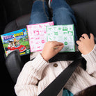 Person sitting in a car with travel games and a bingo card.