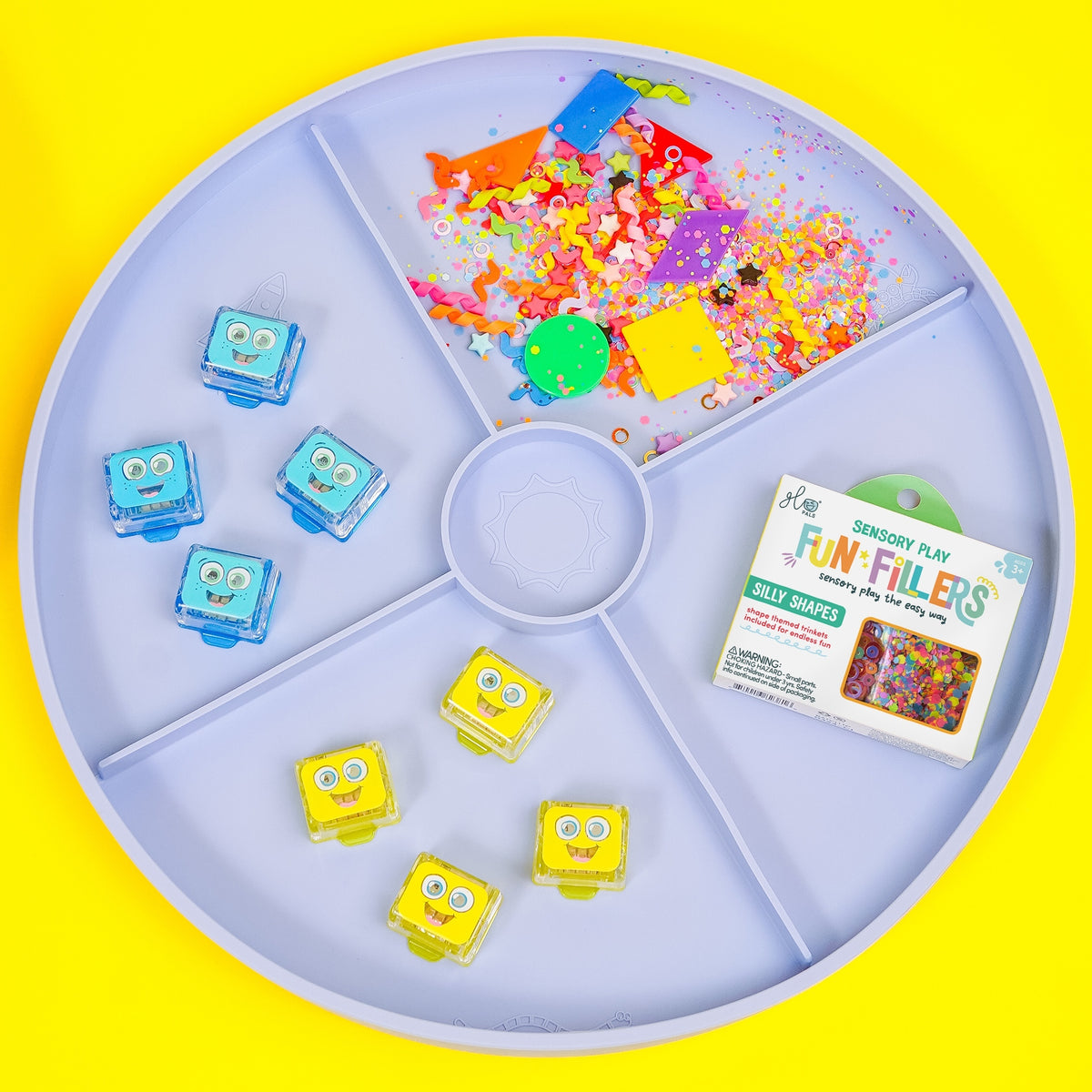 Colorful sensory play items on a round tray with a yellow background