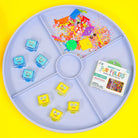 Colorful sensory play items on a round tray with a yellow background