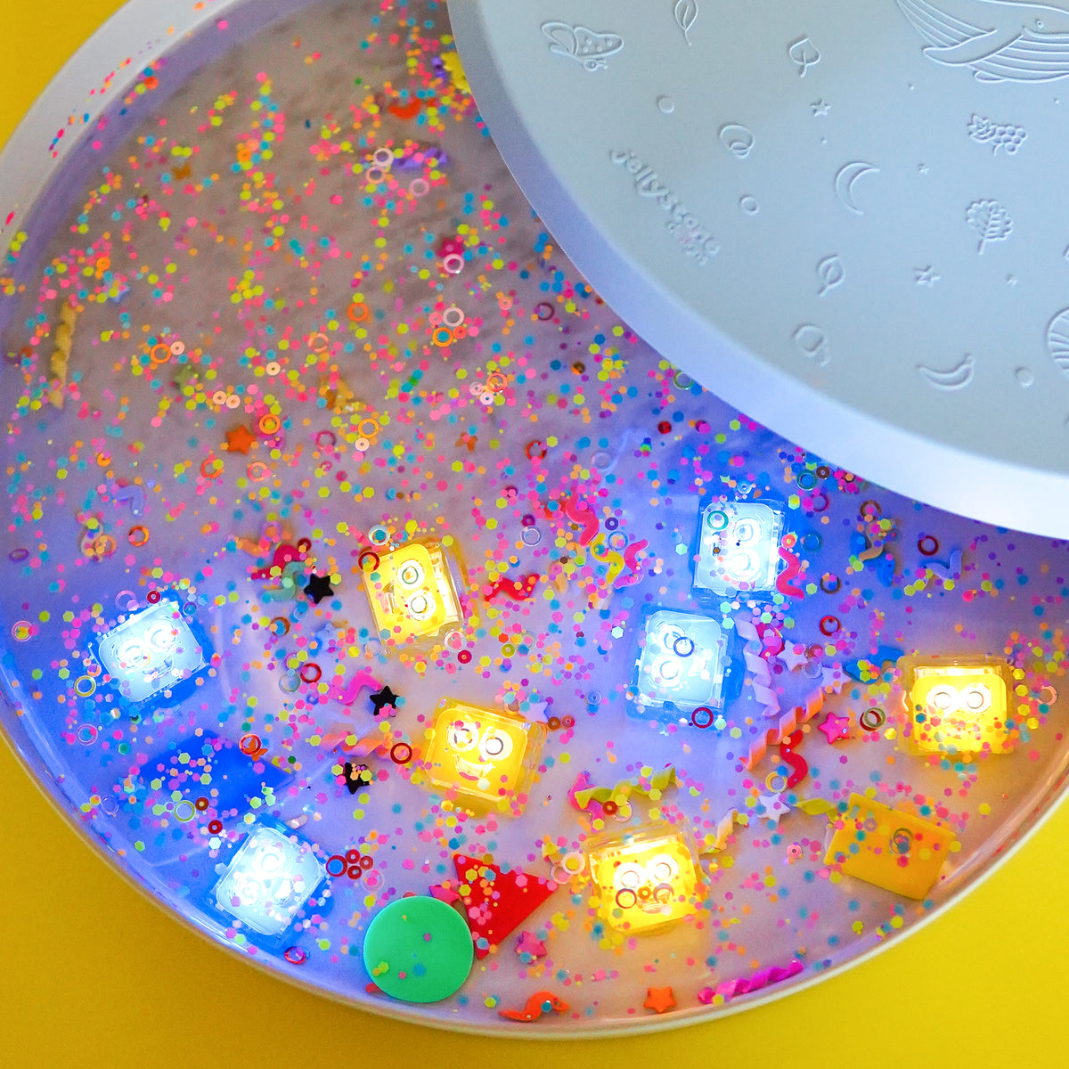 Colorful slime with glowing cubes and confetti in a container on a yellow background