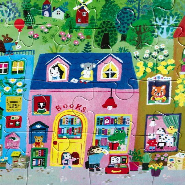 Completed 20 Piece Puzzle - Yumi's Village by Eeboo, featuring a charming bookstore storefront with whimsical animal characters, colorful book displays, and a green countryside backdrop.