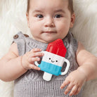 Baby holding a colorful popsicle-shaped toy with a neutral background