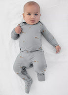 A baby wearing a sage grey günamüna Convertible Footie Pajama patterned with tiny dogs.