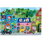 Completed 20 Piece Puzzle - Yumi's Village by Eeboo, displaying a colorful and whimsical village scene featuring various shops, animal characters, a scooter, and a green countryside backdrop.