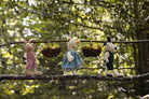 Three stuffed animals on a branch with fruit baskets against a natural background