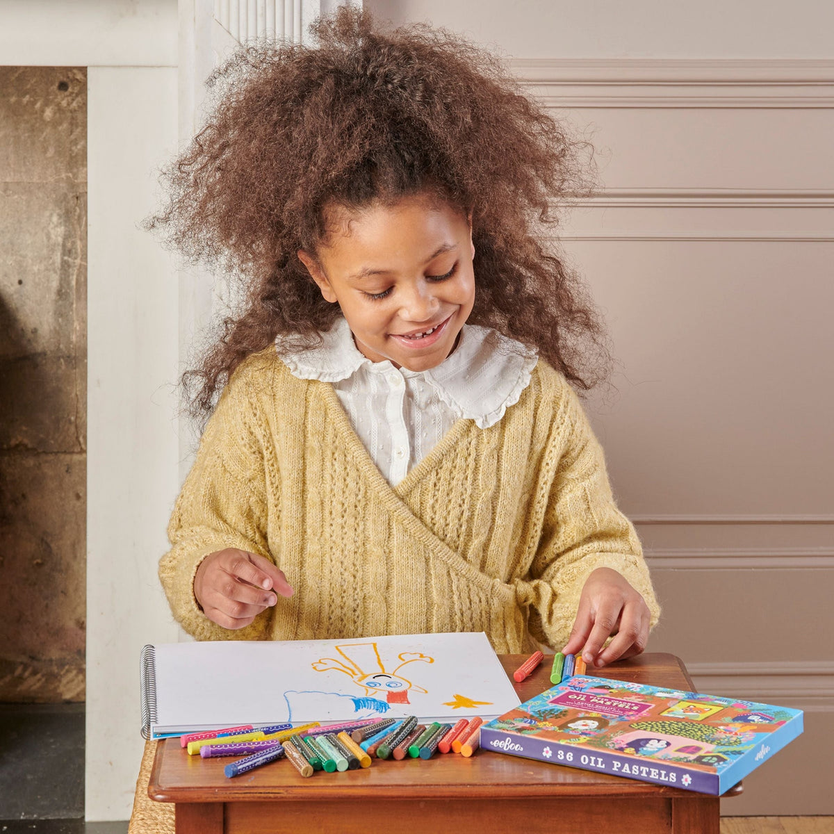 Child drawing with oil pastels on a table in a home setting