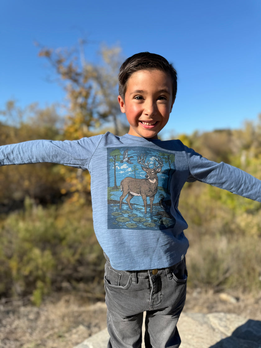 A young person wearing a blue long-sleeve graphic tee with a deer print.