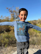 A young person wearing a blue long-sleeve graphic tee with a deer print.