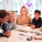 Family playing a board game together in a bright room with large windows.
