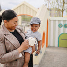 Woman holding a child with a playground in the background