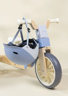 Children's balance bike with a helmet attached on a light beige background