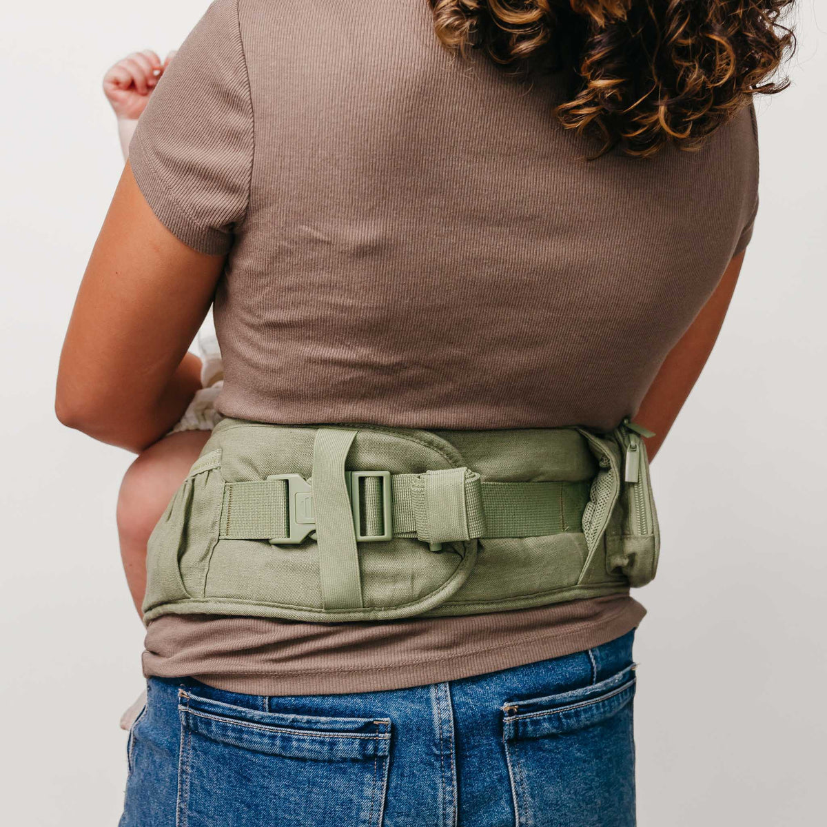 Person wearing a green tactical belt with a plain background