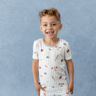 Child wearing a pajama set with sports-themed print against a blue background