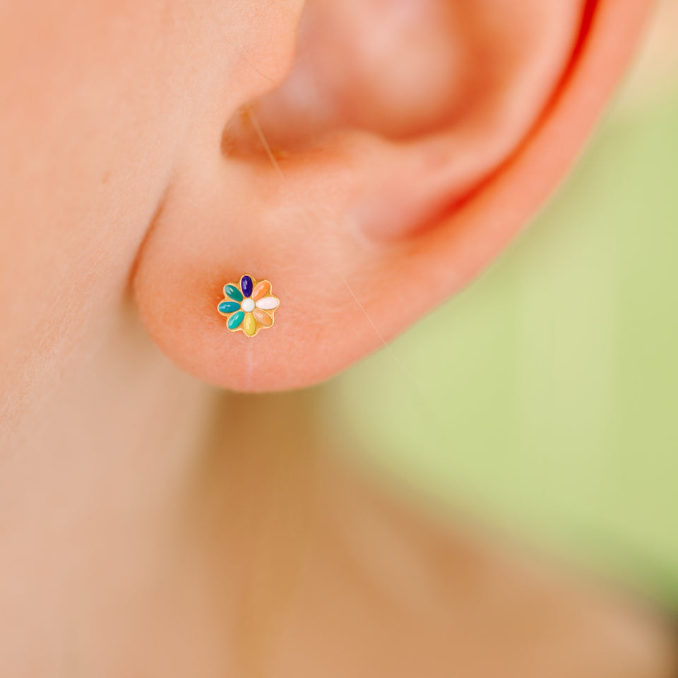 Close-up of an ear wearing a colorful floral earring with a blurred background